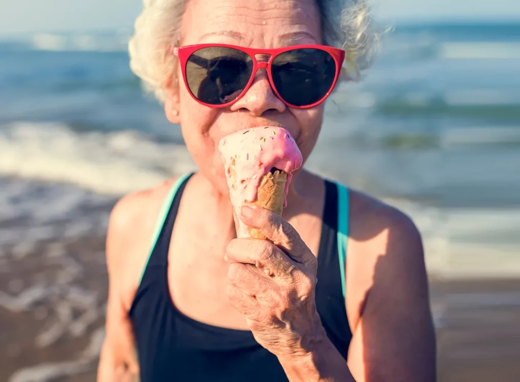 Elder woman eating ice cream on the beach